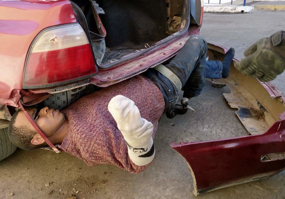 Un inmigrante ilegal descubierto en el parachoques de un coche.