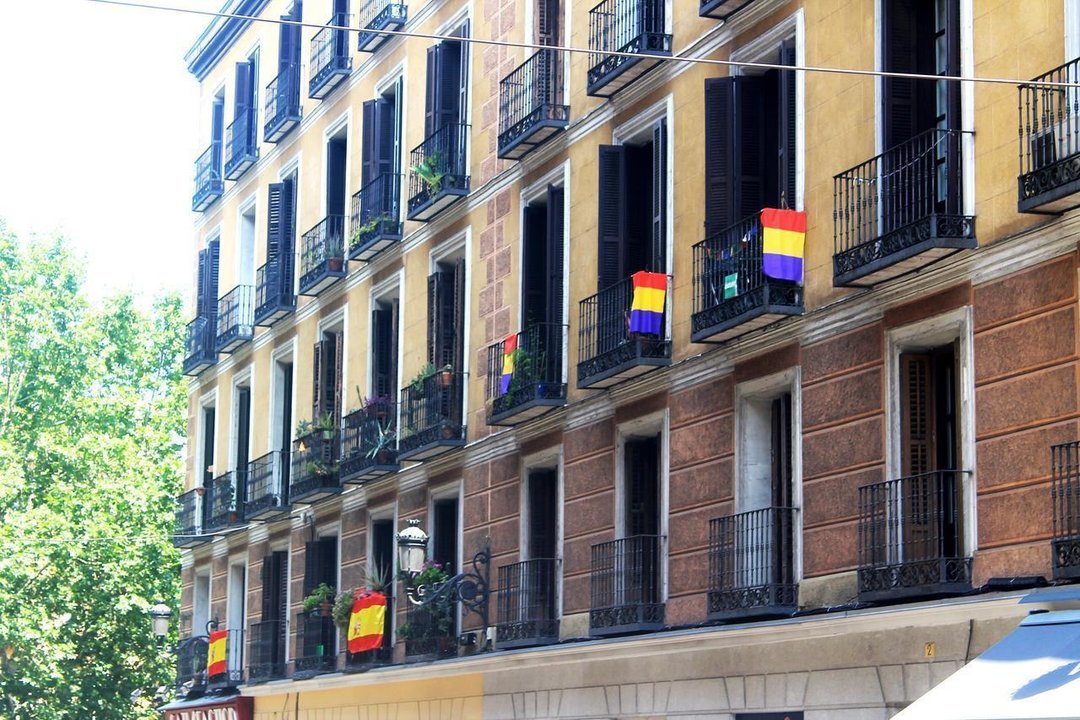 Banderas rojigualdas y tricolores en balcones de una calle de Madrid.