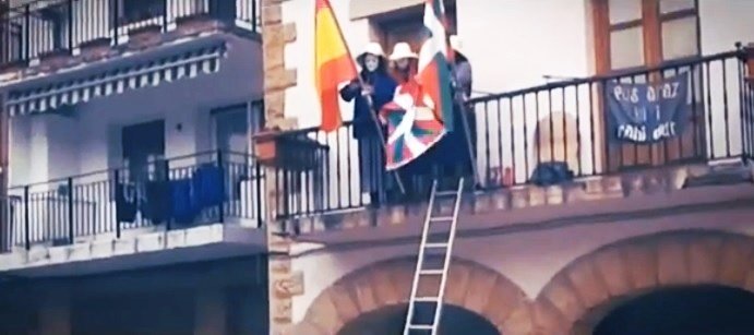 Encapuchados de Ernai retiran la bandera de España del balcón de un ayuntamiento.