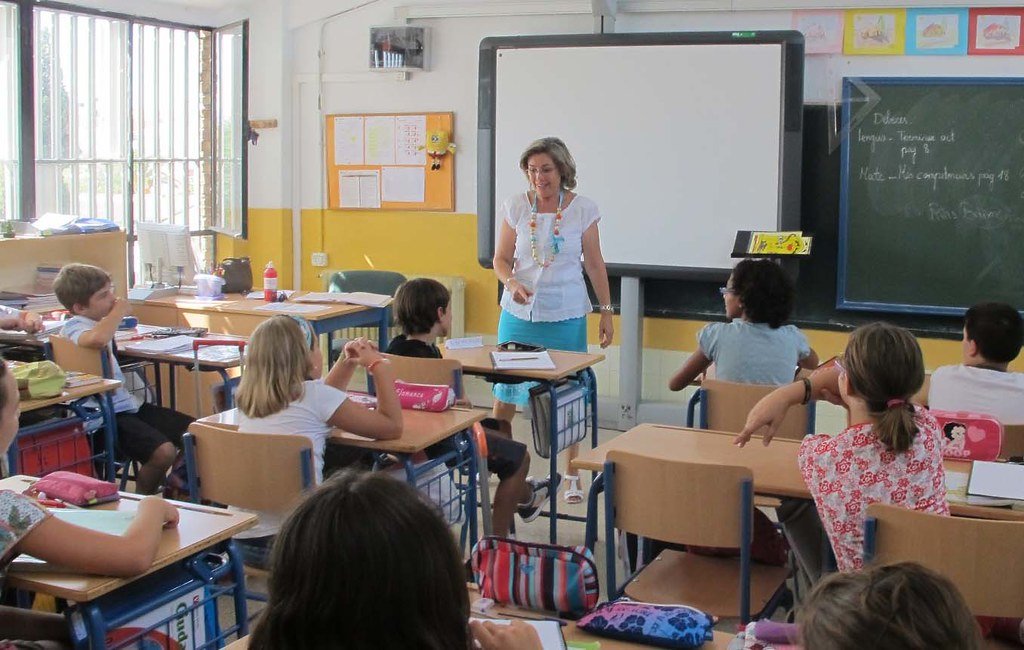 Maestra impartiendo clase a niños de primaria.