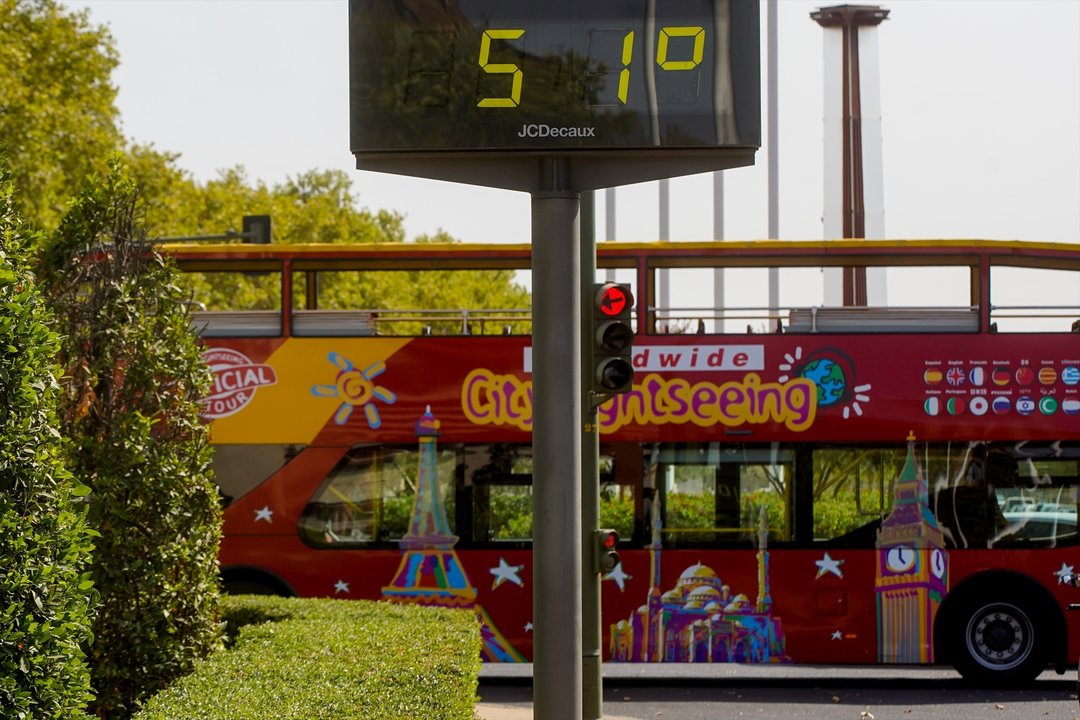 Un autobús turístico pasa sin pasajeros delante de un termómetro que marca 51º en otro día con altas temperaturas en la capital andaluza a 25 de julio del 2022 en Sevilla (Andalucía, España)