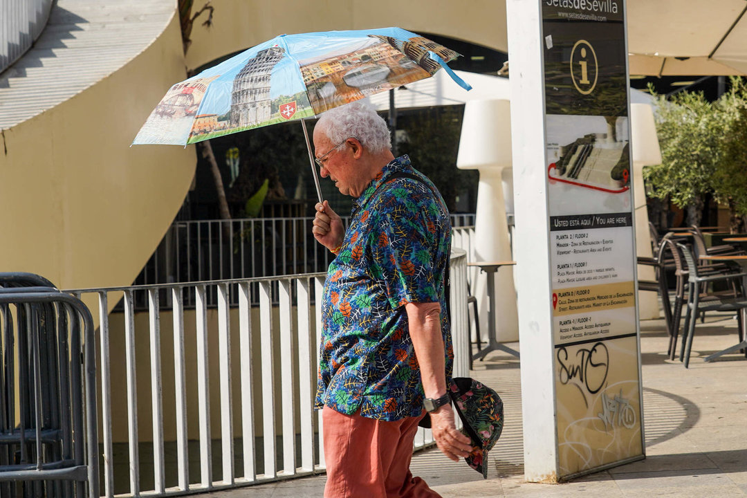 Un turista con un paraguas por las altas temperaturas en la capital andaluza. 