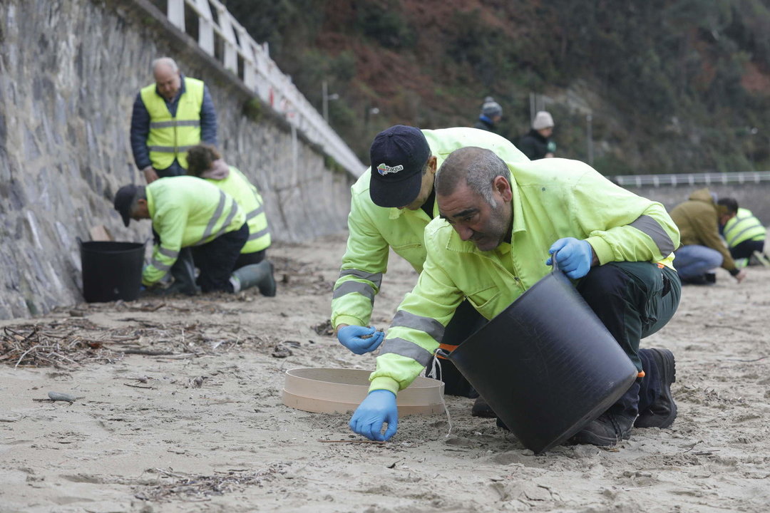 Operarios de TRAGSA recogen pellets de plástico, en la playa de Aguilar, en Muros de Nalón, Asturias. 