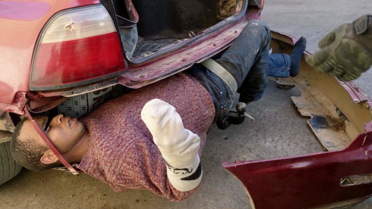 Un inmigrante ilegal descubierto en el parachoques de un coche.