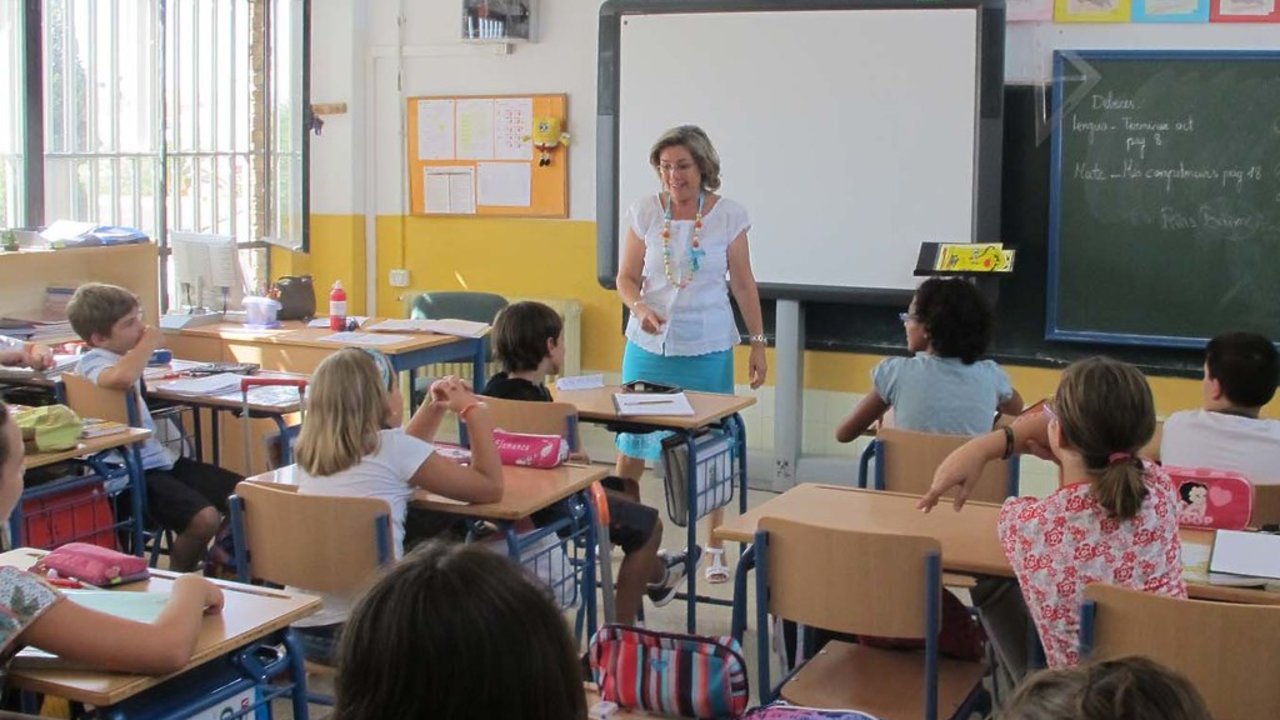 Maestra impartiendo clase a niños de primaria.