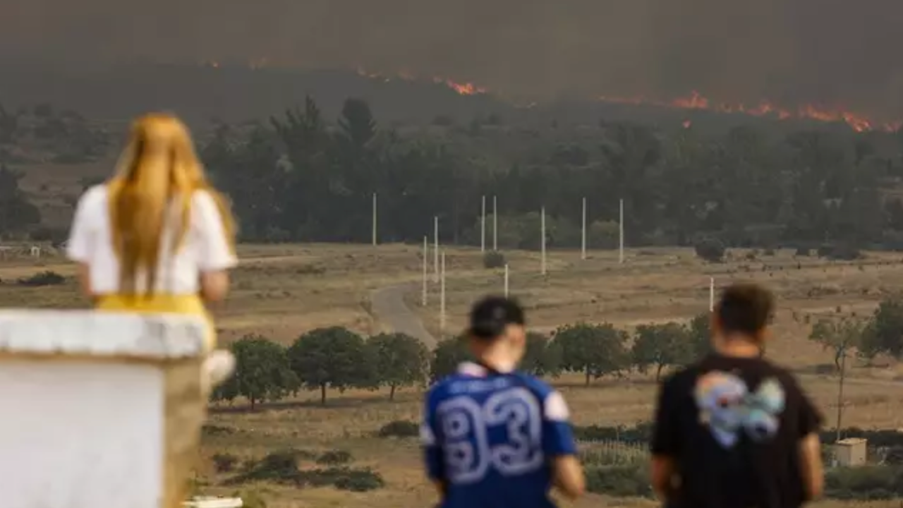 Varias personas observan las llamas y el humo del incendio en Bejís desde el municipio de El Toro