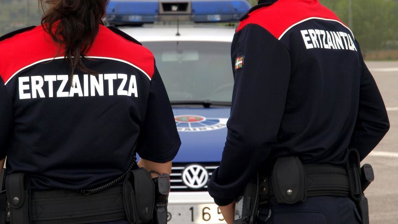 Agentes de la Ertzaintza junto a un coche patrulla.