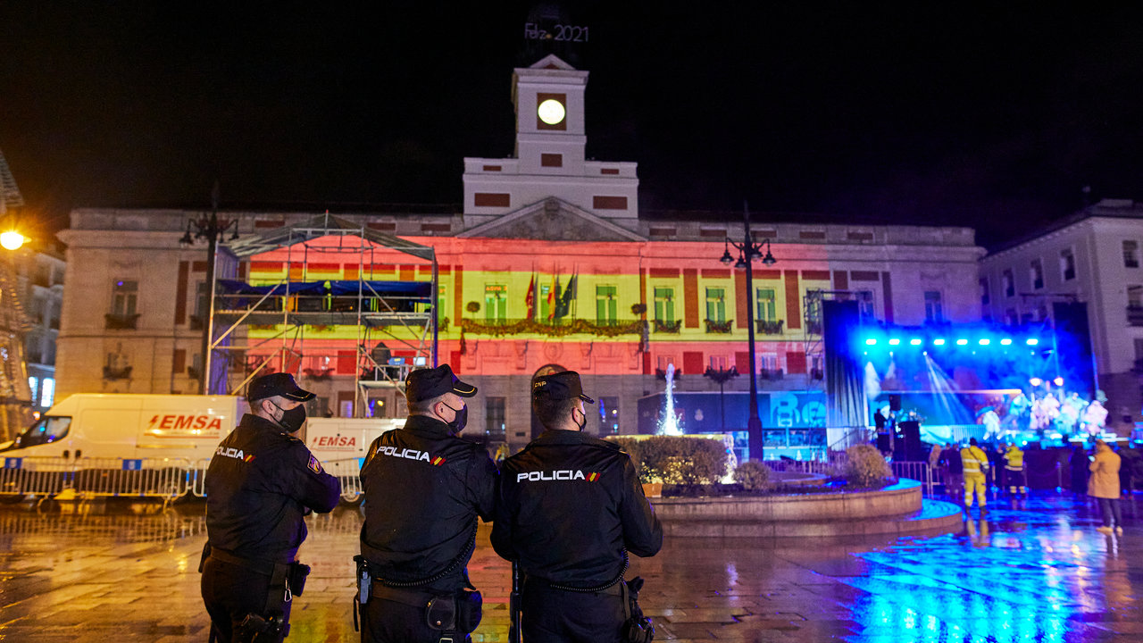 Tres policías nacionales observan el concierto de Nacho Cano en la Puerta del Sol, en Madrid (España), a 31 de diciembre de 2020. Nacho Cano ha actuado esta Nochevieja con una sola canción minutos antes de las campanad